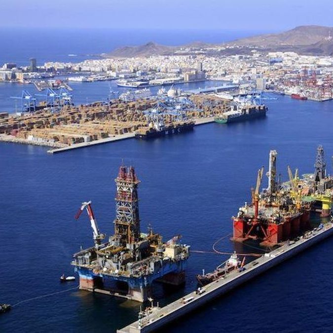 Consultoría Plataforma petrolera en el mar, con puerto y ciudad al fondo.